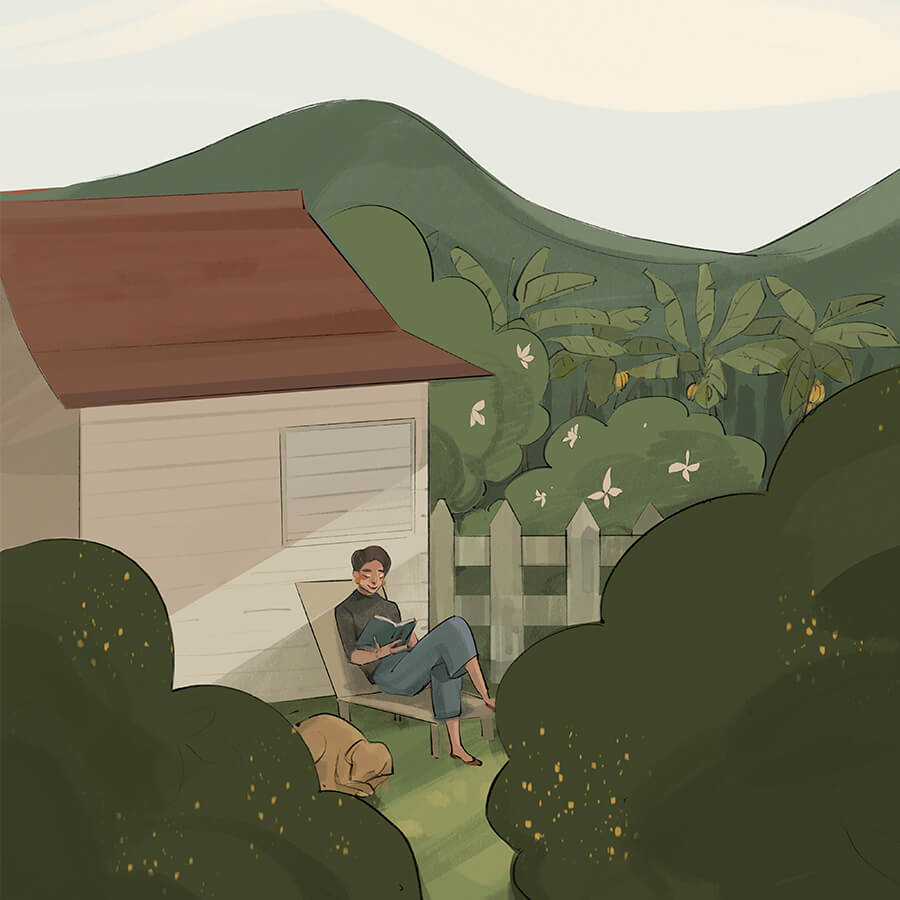 Blaise reads a book outside her home in a hillside area. Banana trees sit at the base of the nearby hills.